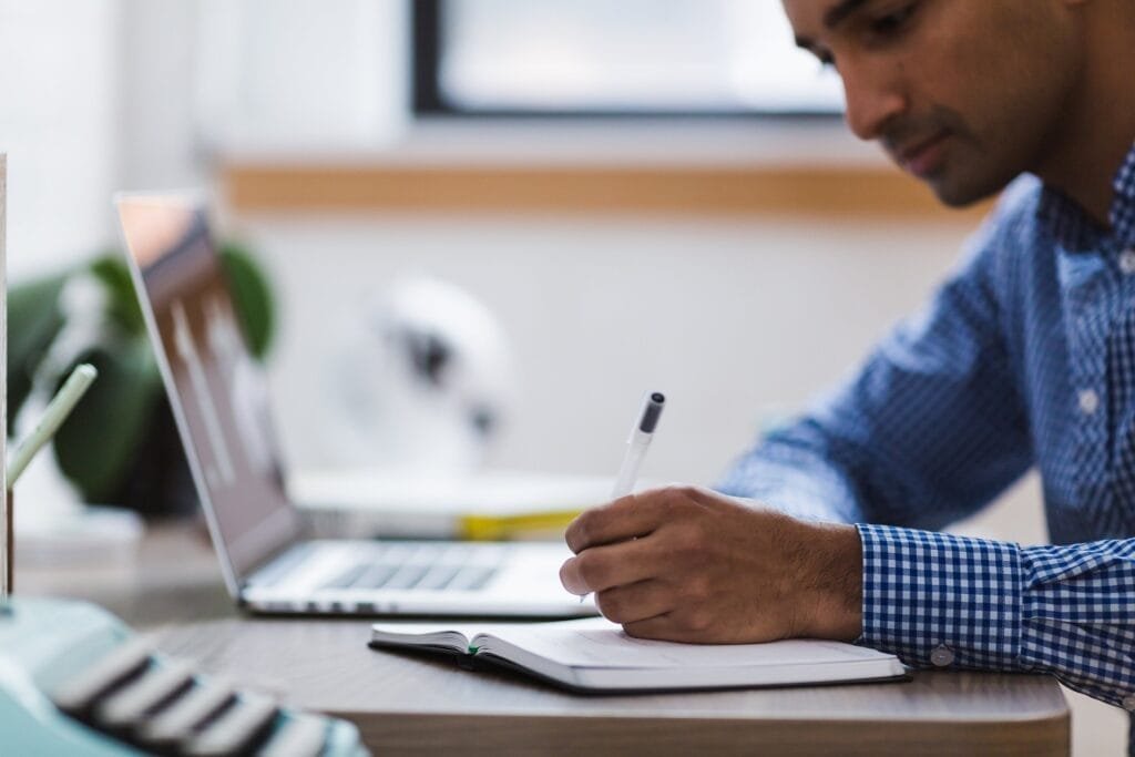 Man writing in front of laptop: our unbreakable editorial standards